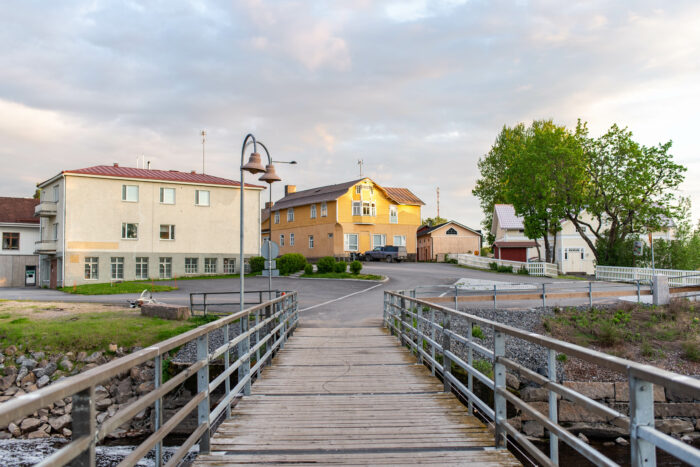 joen ylittävä kävelysilta ja kaksi keltaista taloa