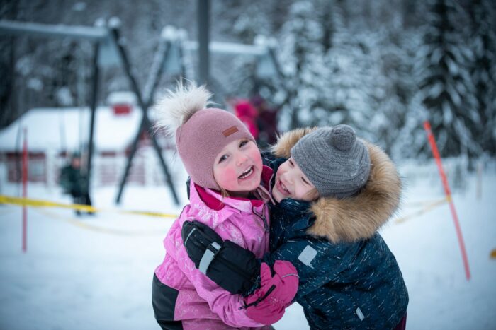 kaksi lasta halaa toisiaan talvisessa päiväkodin pihassa