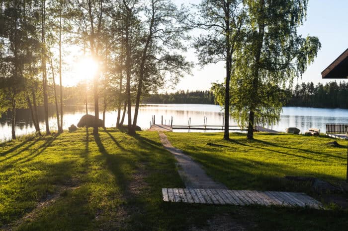 auringonlasku kuva rannalta, puita ja laituri