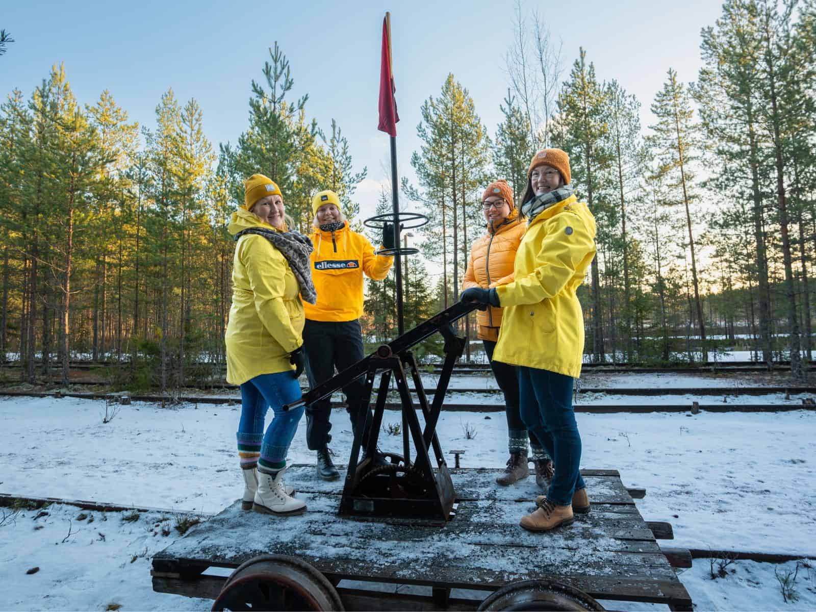 Resiina, neljä henkilöä, lunta ja puita.