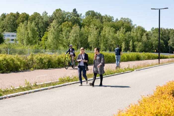 Pyöräilijä, sähköpotkulautailija ja jalankulkijat liikenteessä.