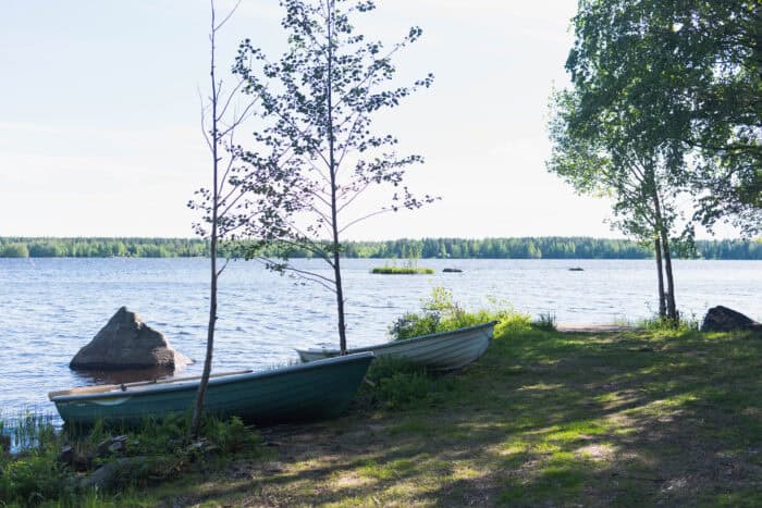 "Vettä, ranta, soutuveneitä, puita."